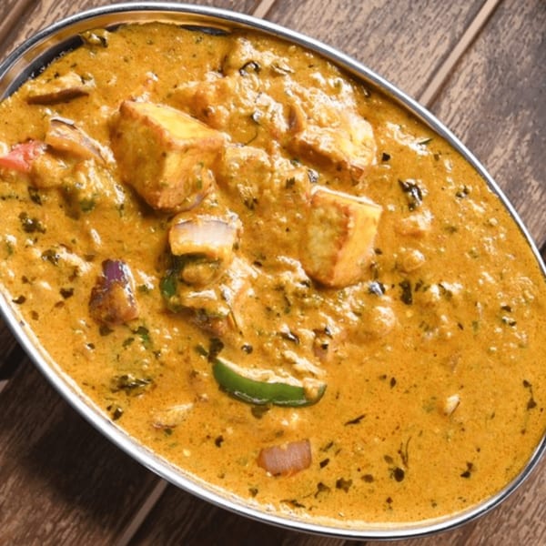 Mirchi Indian Cuisine's paneer butter masala, a creamy orange curry with paneer, onions, and peppers.