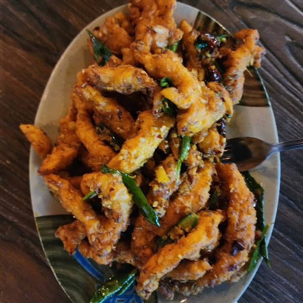 Crispy fried Indian chili chicken or paneer, garnished with green chilies, on a decorative plate.