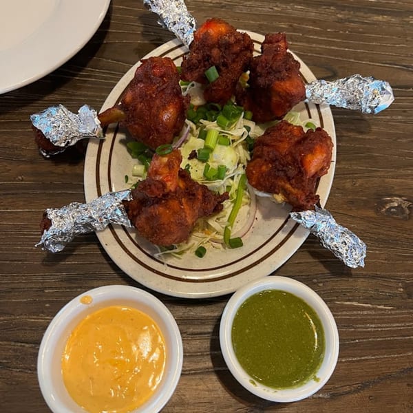 Mirchi Indian Cuisine's chicken lollipops with foil-wrapped bones, served with shredded cabbage and two dipping sauces.