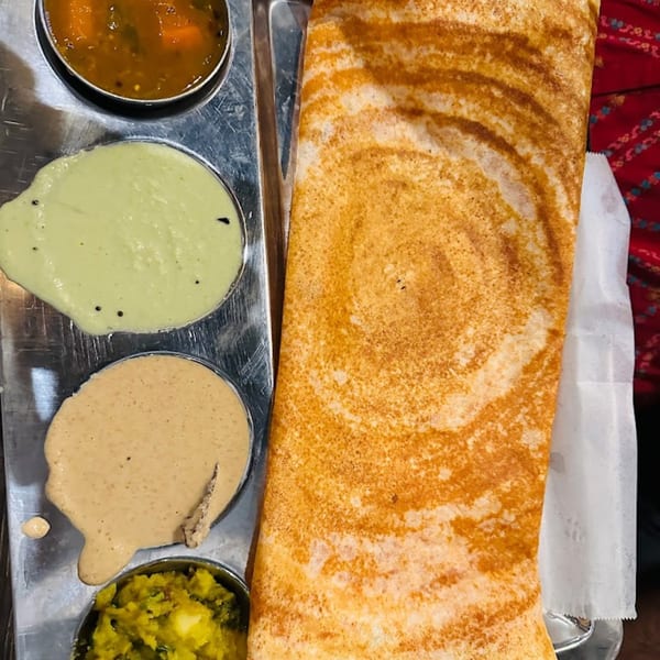 Crispy golden dosa with three chutneys and sambar on a metal tray at Mirchi Indian Cuisine.